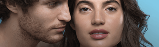 Close up of a man and woman's faces in front of blue background