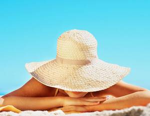 Woman in sun hat lying on sunny beach